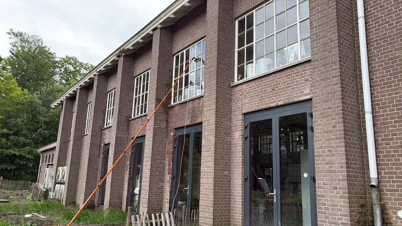 A telescopic pole at the high windows of a brick business building.