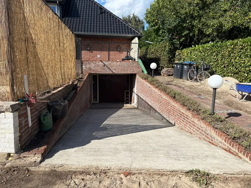 A cleaned driveway with brick walls beside a home.