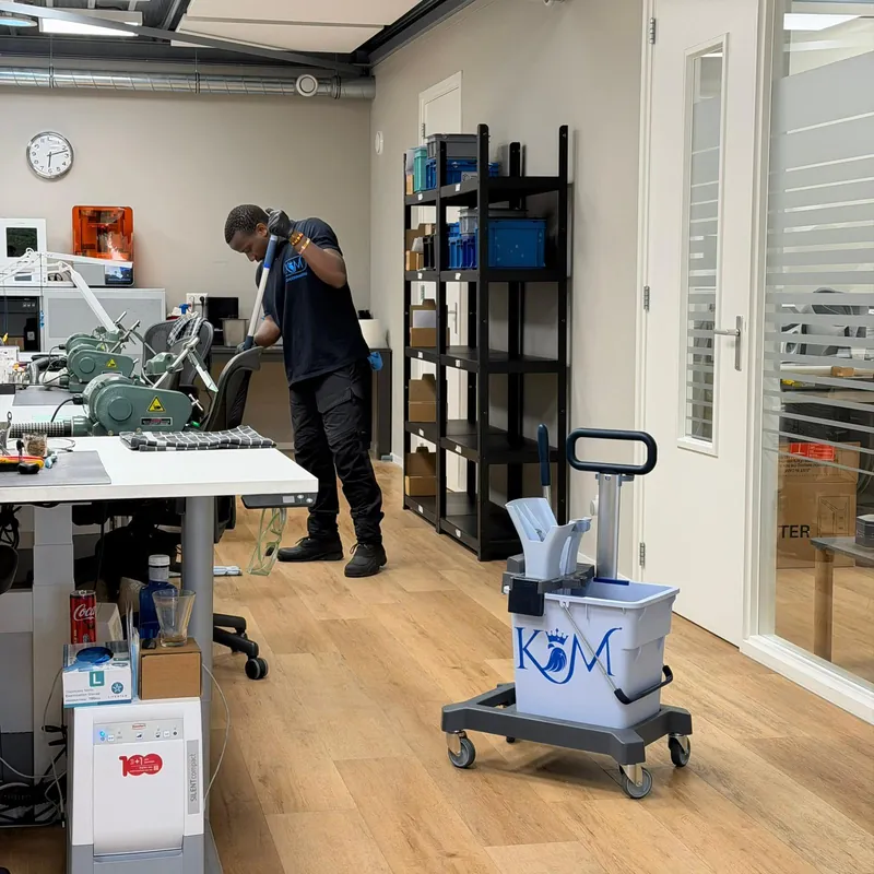 A KM team member at work in an office with a KM cleaning trolley.