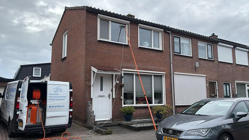 The white KM van with cleaning equipment beside a home during window cleaning.